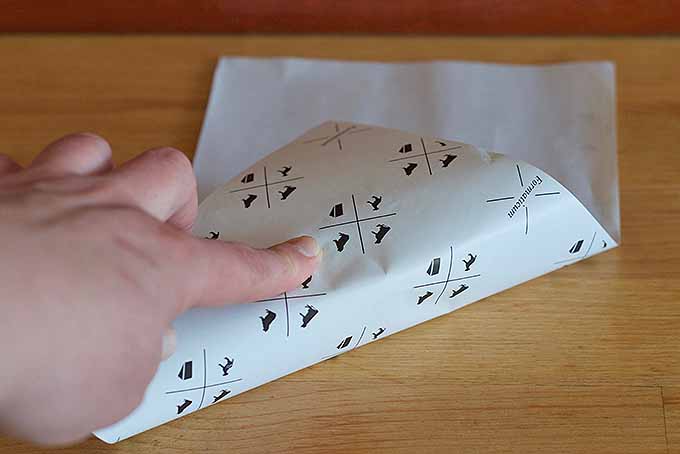 Folding paper over a wedge of cheese | Foodal.com