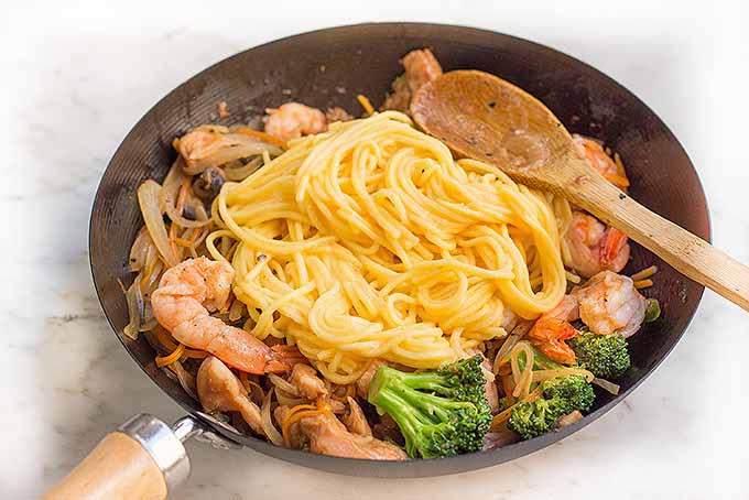 Adding noodles to finish the lo mein dish | Foodal.com