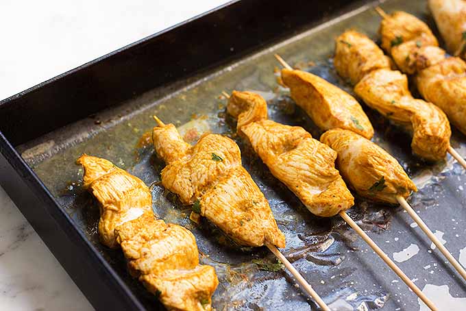 Cooking chicken satay skewers for a spicy handheld dinner. | Foodal.com