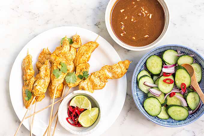 The perfect handheld dinner: spicy peanut chicken satay with a cucumber salad on the side. | Foodal.com