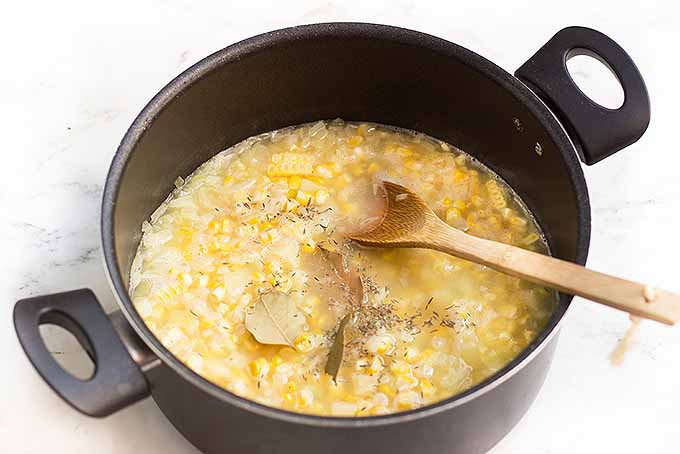 Adding in flavorings to a pot of the best corn chowder. | Foodal.com