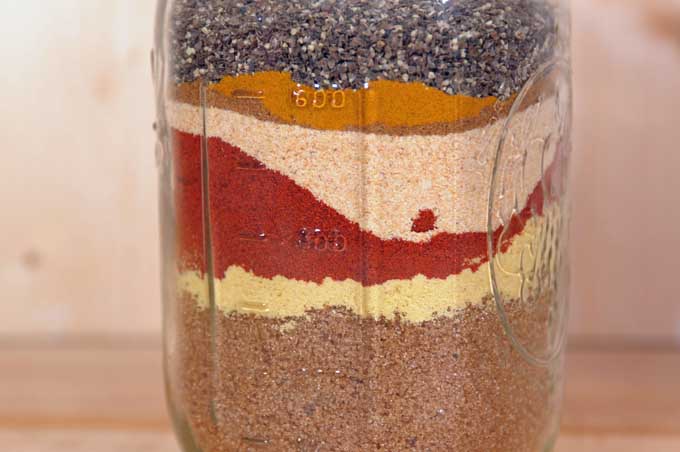 Colorful layers of spices in mason jar.