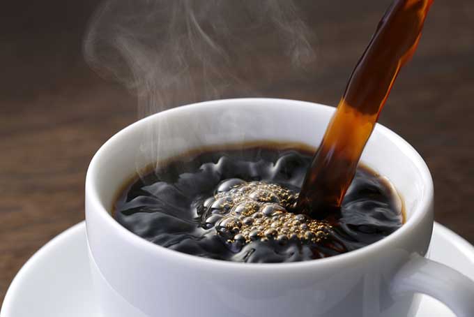 A white coffe cup with liquid being poured in.
