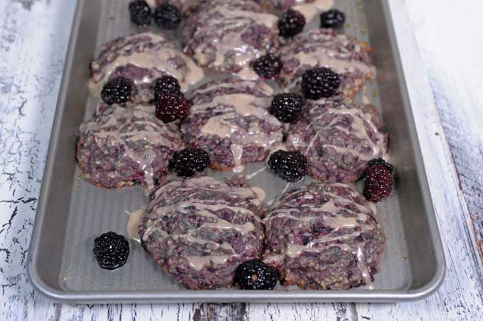 Blackberry scones on a cookie tray sitting on a rustic wooden table.