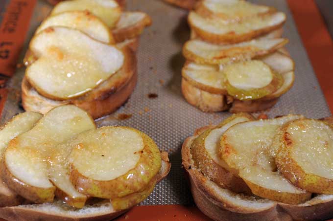 Close up of baked crostini on a Silpat baking mat on a cookie sheet | Foodal