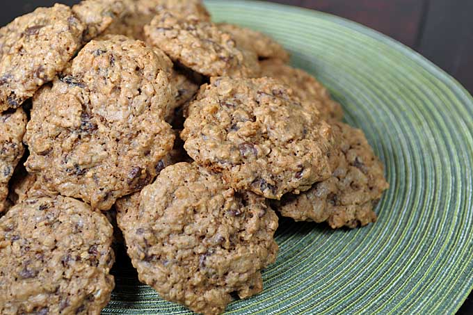 A pile of oatmeal chocolate chip cookies on a green circular place mat | Foodal 