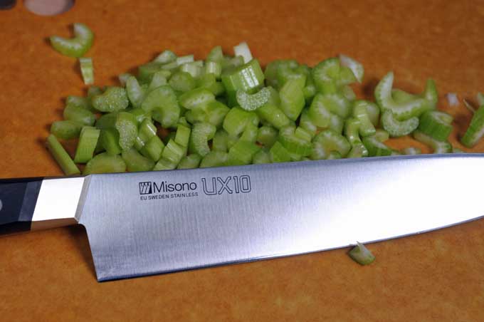 Misono Gyuto Chef Knife in the foreground and chopped celery in the background. Sitting on a Epicuran cutting board | Foodal
