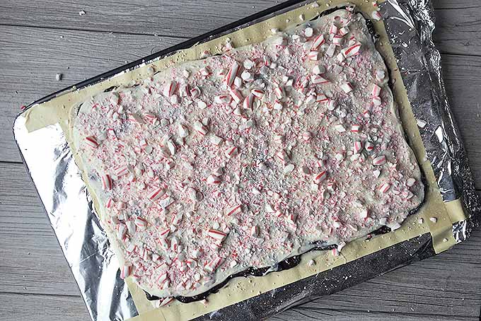 A third layer of white chocolate has been spread over the first two layers with candy cane crumbles spread on top of that.
