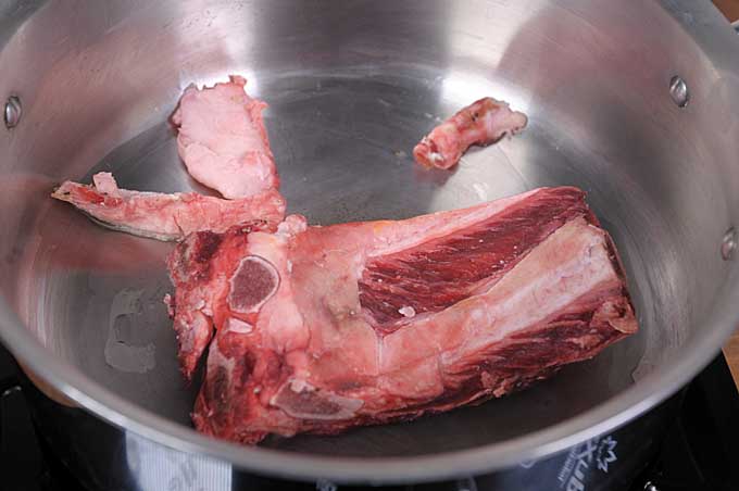 Beef rib bones and fat added to a stock pot | Foodal