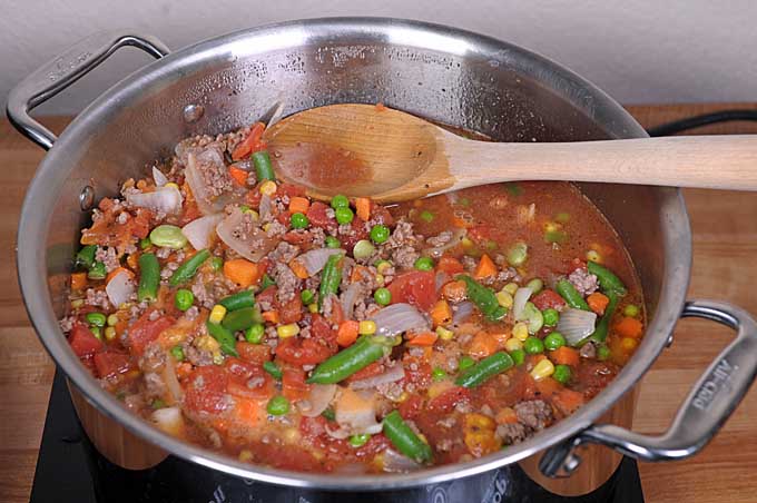 Hamburger soup with all of the ingredients added to the stockpot and simmering on the stove | Foodal