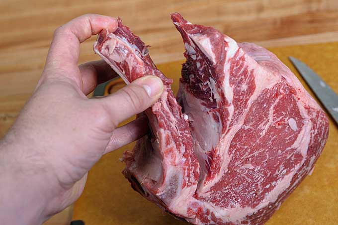A rib roast with the bones nearly cut away and only being held by the flesh around the "top rib" | Foodal