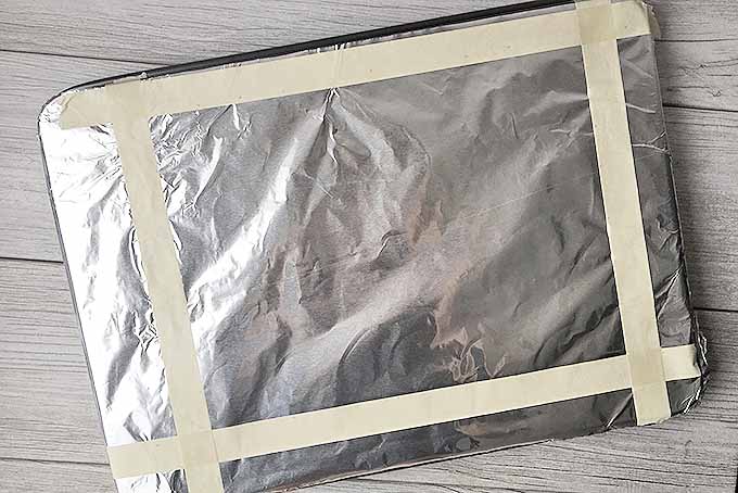 Top down view of a baking sheet with aluminum foil attached to the top.