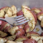 A close up of a fork showing a single piece of a roasted rosemary red potato | Foodal