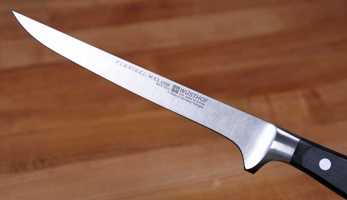 Wusthof Classic Flexible Boning Knife with a medium toned cutting board as a background | Foodal