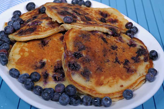 A white oblong platter with 8 giant blueberry buttermilk pancakes filling the plate | Foodal