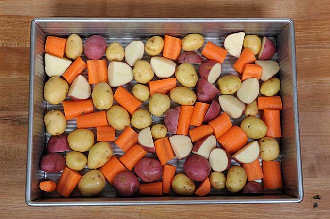 A cake pan full of multicolored baby potatoes and carrots | Foodal
