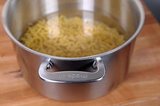 Elbow macaroni added to a a Made-In stockpot. 
