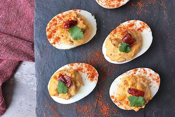 Horizontal image of deviled eggs with chipotle on a slate with a red towel