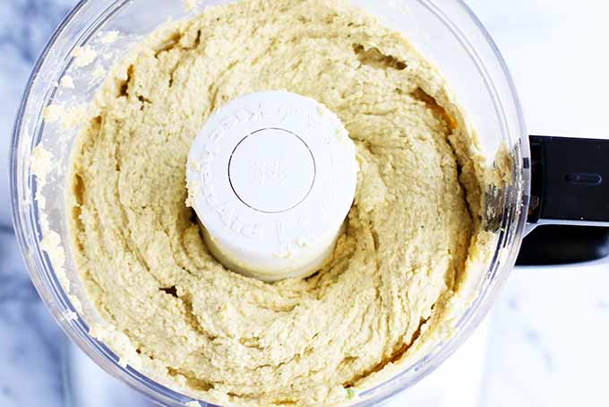 Horizontal image of a chickpea puree in a food processor. 