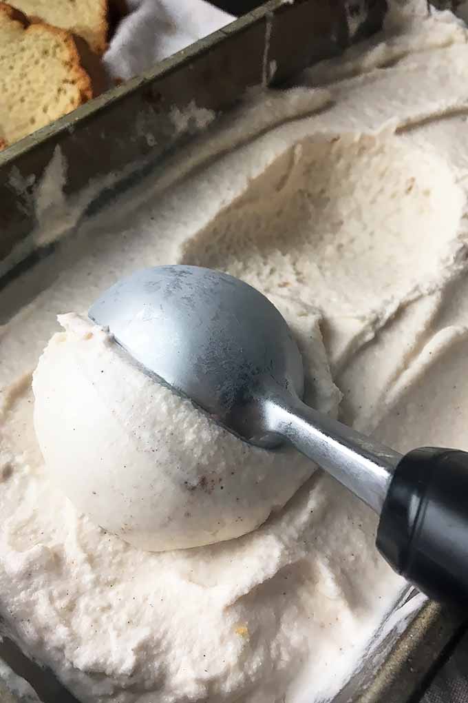 Vertical image of scooping out white ice cream from a pan.