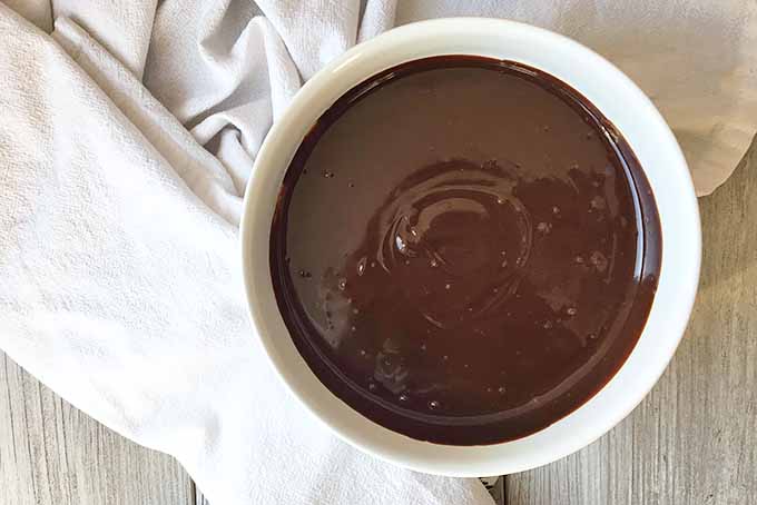 Horizontal image of ganache in a white bowl on a white towel.