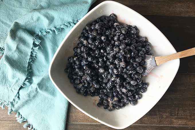 Horizontal image of a bowl of blueberry pie filling on a blue towel.