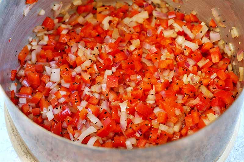 Red bell pepper and onion relish in a saucepan.
