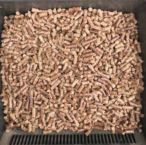 A close up of a hopper of a pellet grill showing food-grade hardwood-based pellets.