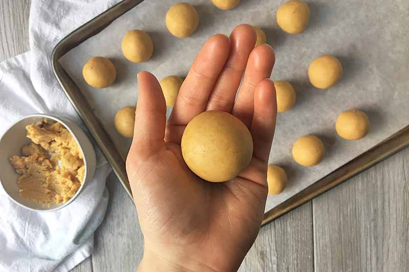 Horizontal image of a hand with a perfectly shaped yellow cake ball.