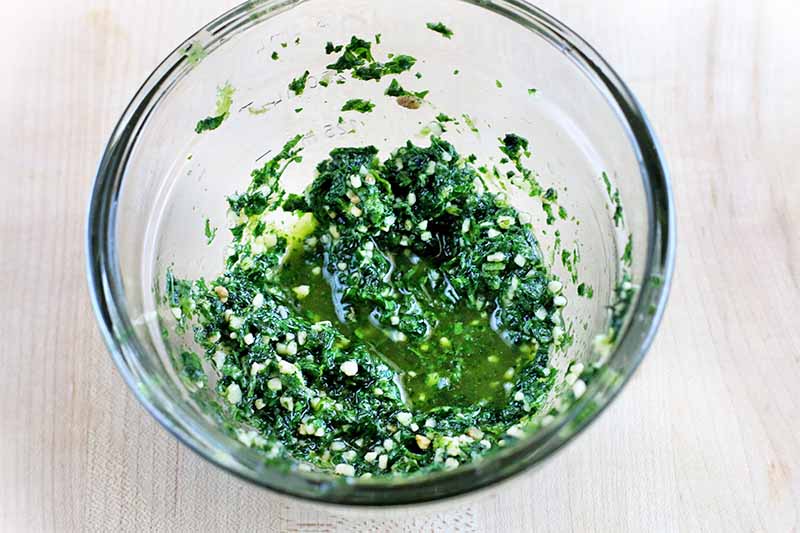 A glass dish of honey lime marinade, with chopped cilantro and minced garlic.