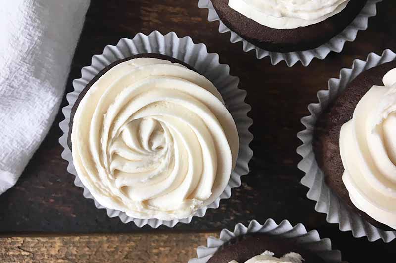 Horizontal image of cupcakes with white piped frosting.