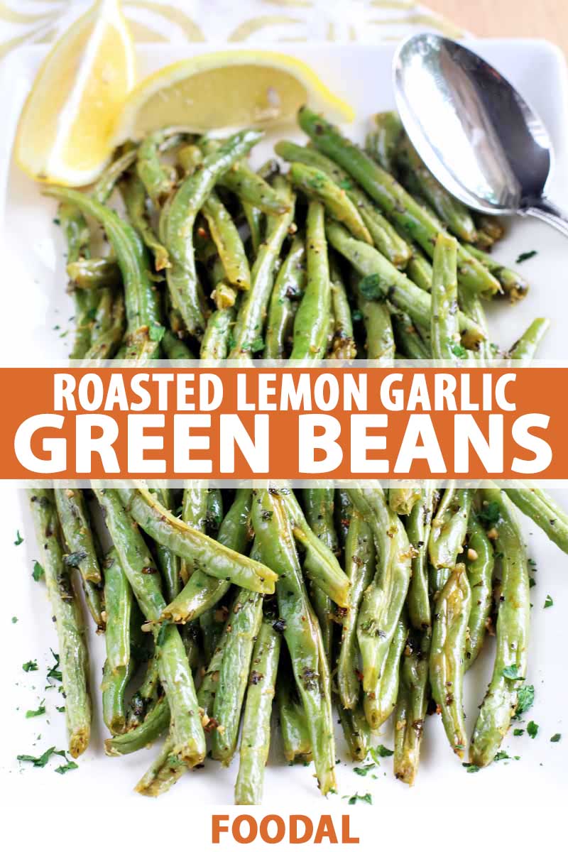 Top down view of roasted garlic green beans with lemon wedges, a spoon, and a sprinkling of fresh herbs, on a square white serving dish.