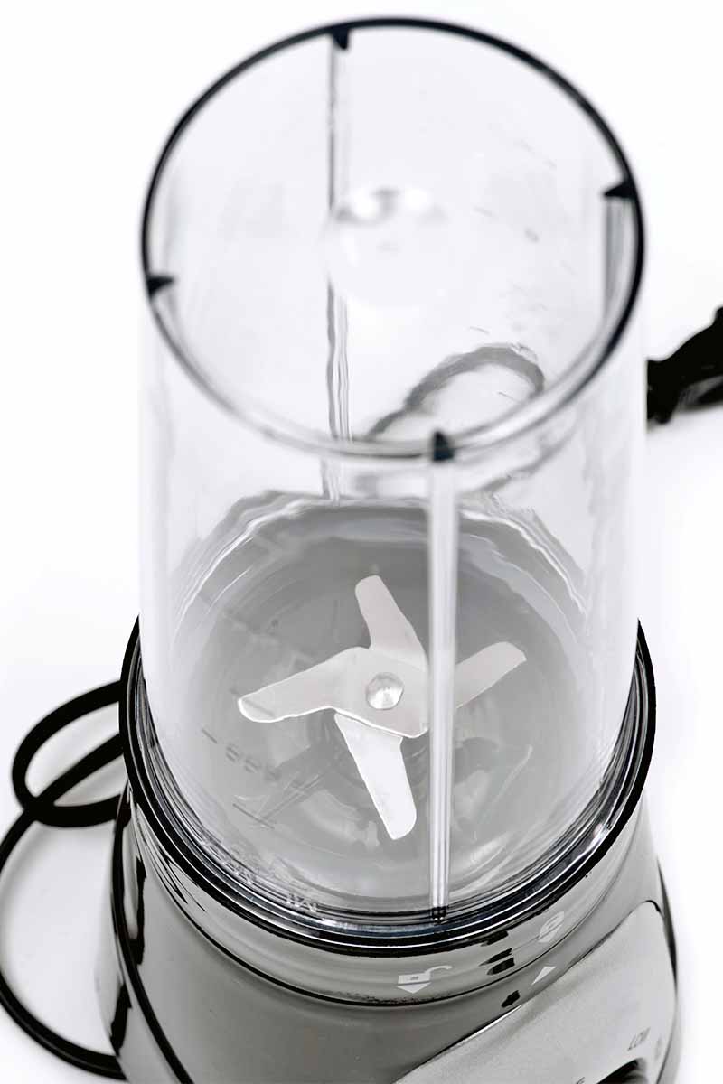 A personal blender with clear canister, gray base, and black power cord, isolated on a white background.