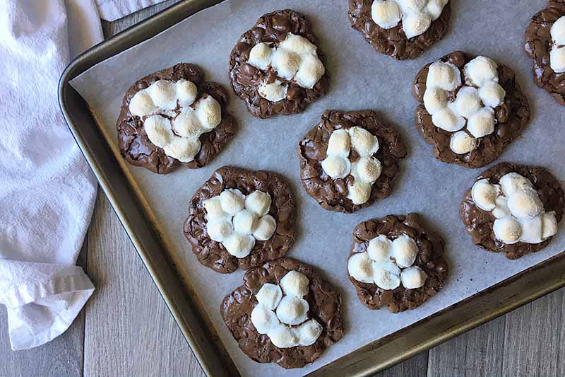 Horizontal image of baked cookies with mini marshmallows on a sheet pan.