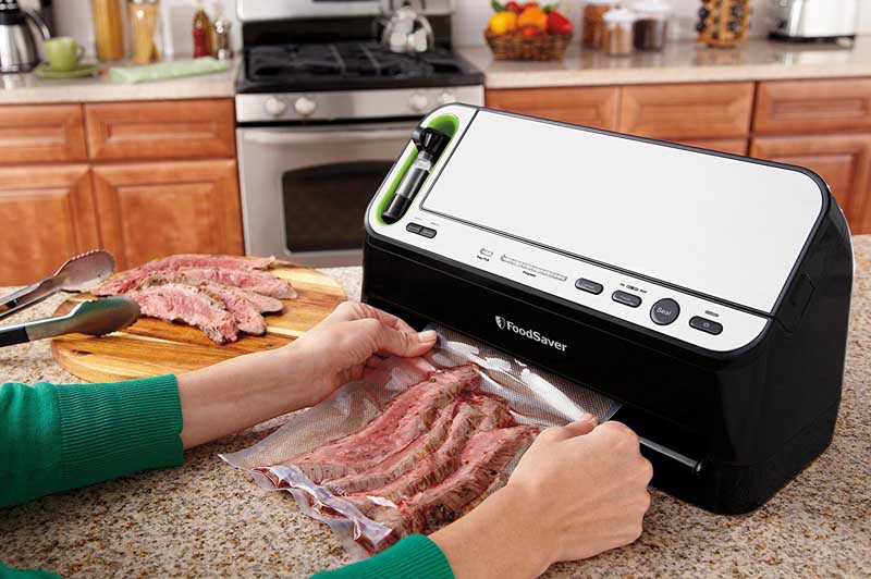 Human hands in a kitchen environment using the FoodSaver Vacuum Sealer V4440 2-in-1 Automatic System to seal up steak.