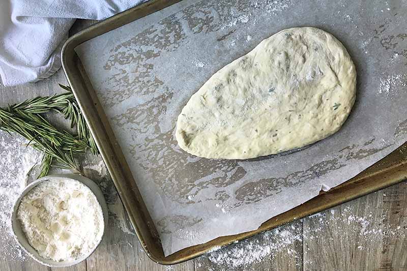 Horizontal image of a shaped dough on a baking pan lined with parchment paper.