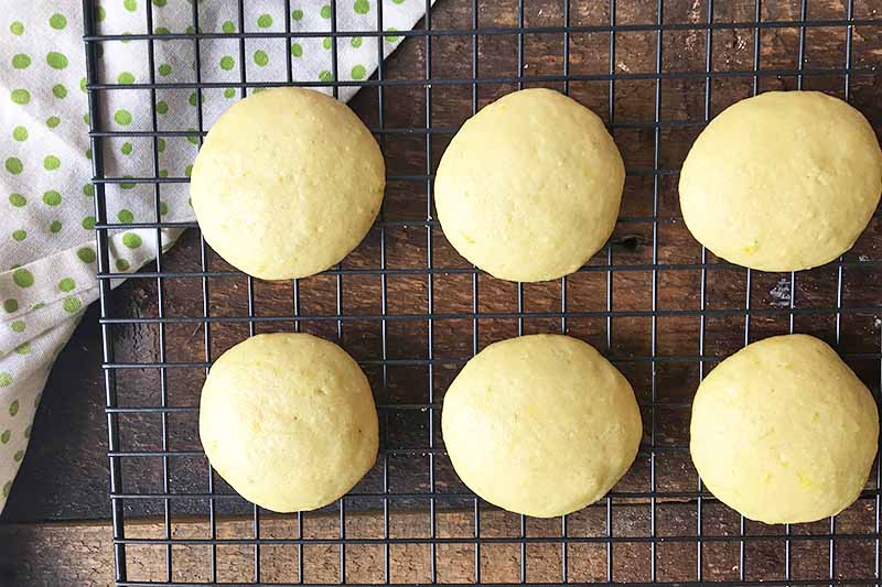 Horizontal image of a cooling rack with baked yellow cake rounds.
