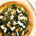 Horizontal top-down image of pizza with kale and goat cheese.