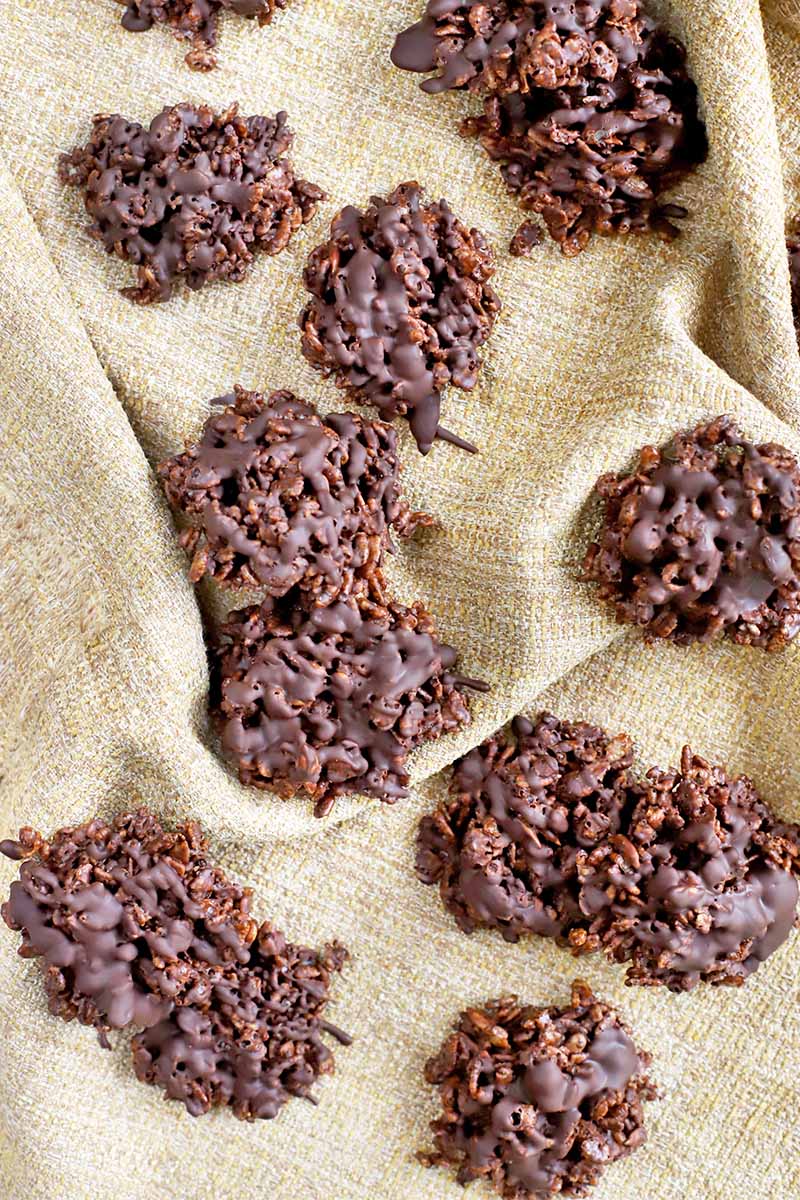 Crisped rice, sunflower seed, and cocoa clusters are scattered haphazardly on a gathered and creased piece of burlap fabric.