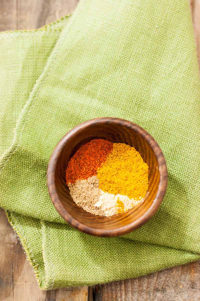 Top down view of a bowl of spice containing garam masala, curry powder, coriander, turmeric, ground ginger, and cumin.