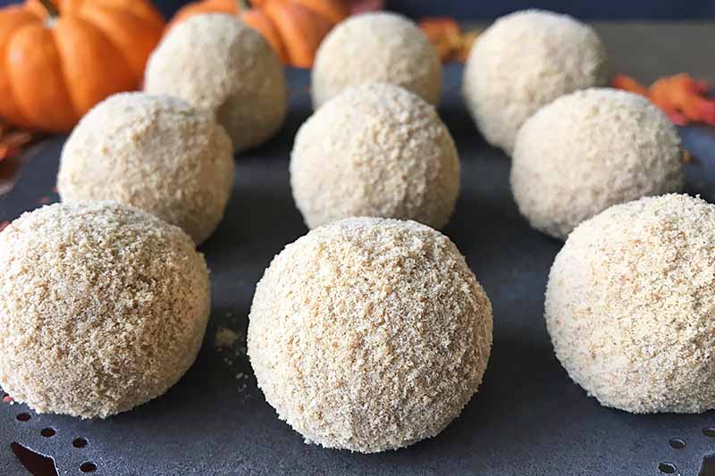 Horizontal image of rows of white chocolate truffles with pumpkins.