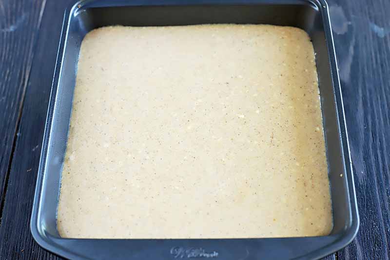Horizontal image of a lightly colored dessert baked in a square pan.