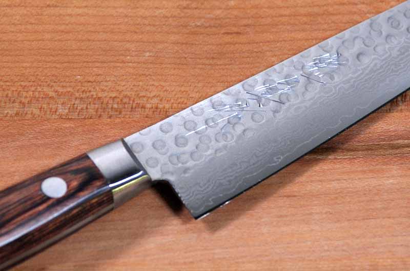 Close up of the blade on the Norisada Hammered Damascus Petty Knife showing the Japanese Kanji Engraving