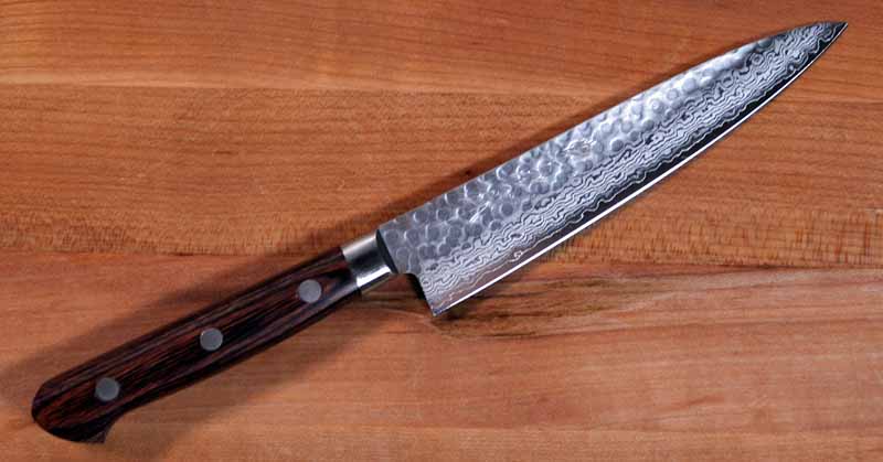 Norisada Hammered Damascus Petty Knife on a maple cutting board.