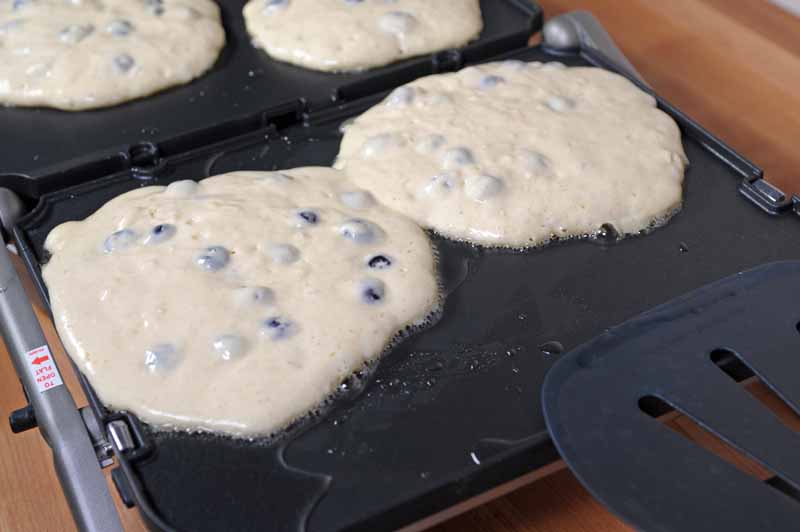 A close up of four large pancakes cooking on the Cusinart GR-4N 5-in-1 Griddler