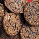Five dark chocolate cookies are arranged on black and white plaid flannel, overlapping at the edges.
