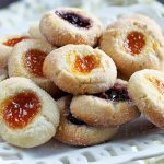 Jam-filled thumbprint cookies on a square white serving dish.