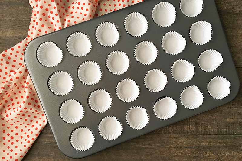 Horizontal image of mini cupcake liners in a pan on a polka dot towel.