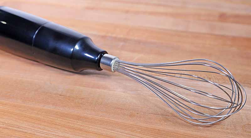 A close up of the wire whisk attached to the KitchenAid KHB2351 motor base.