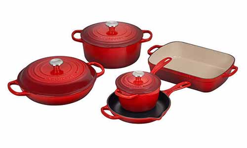 Le Creuset cast iron 6-piece set of cookware, red and beige enamel, isolated on a white background.